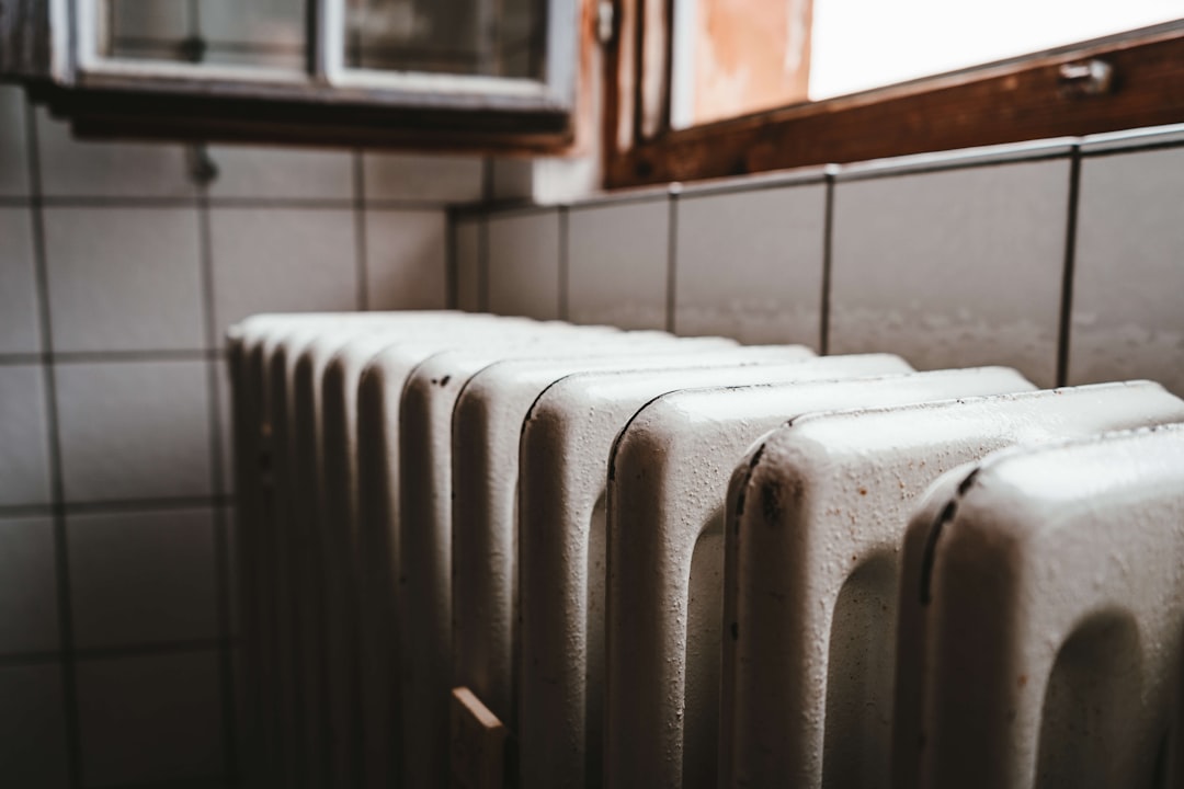 Radiateur sous une fenêtre à menuiserie bois dans un logement ancien mal isolé