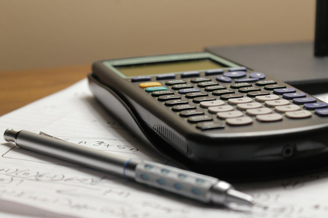 Calculatrice et stylo posés sur des documents pour estimer un bien